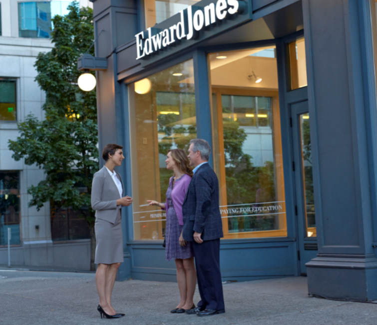 A financial advisor and a couple standing outside an Edward Jones office.