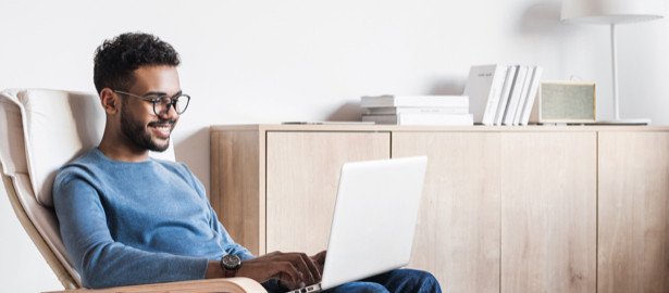 Male sitting on chair, working from home on laptop.