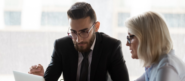 A man and woman looking at the screen of a laptop computer.