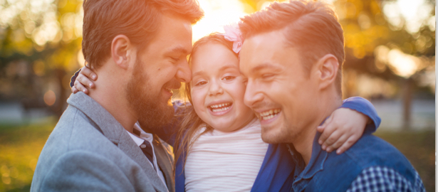 Two gay men hugging their young daughter.