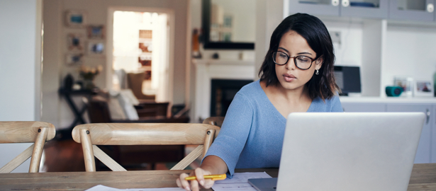 Female working from home at dining room table on laptop.